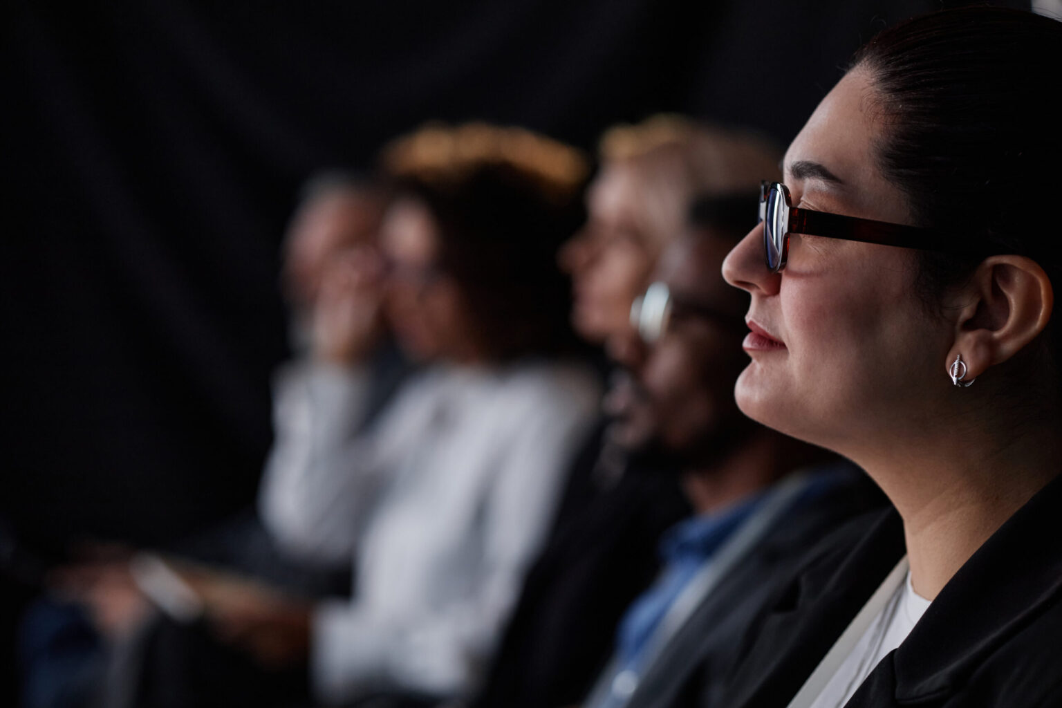 female finance executive with glasses attending summit in conference hall